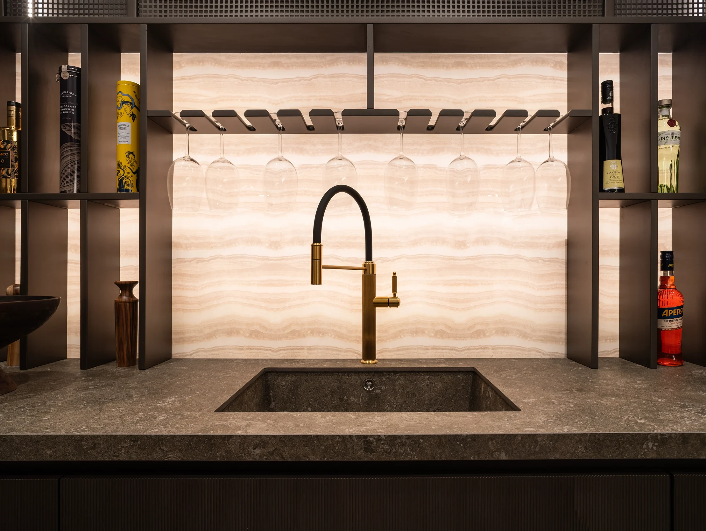 Interior de INKO Estudio Marbella: pared de nogal con puerta de piedra y zona de trabajo con taburetes